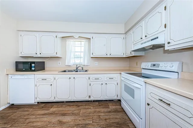 a kitchen with granite countertop white cabinets and white appliances