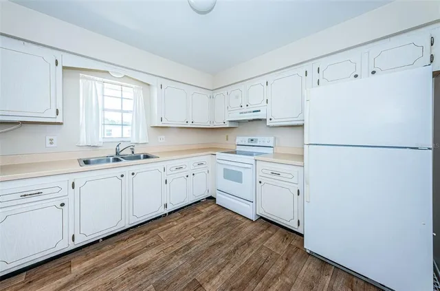 a kitchen with white cabinets white stainless steel appliances and sink