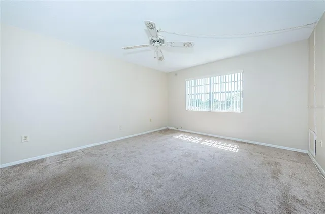 an empty room with a window and a ceiling fan