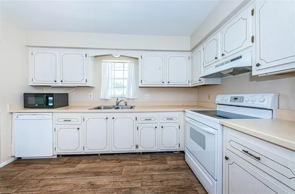 a kitchen with granite countertop white cabinets and white appliances