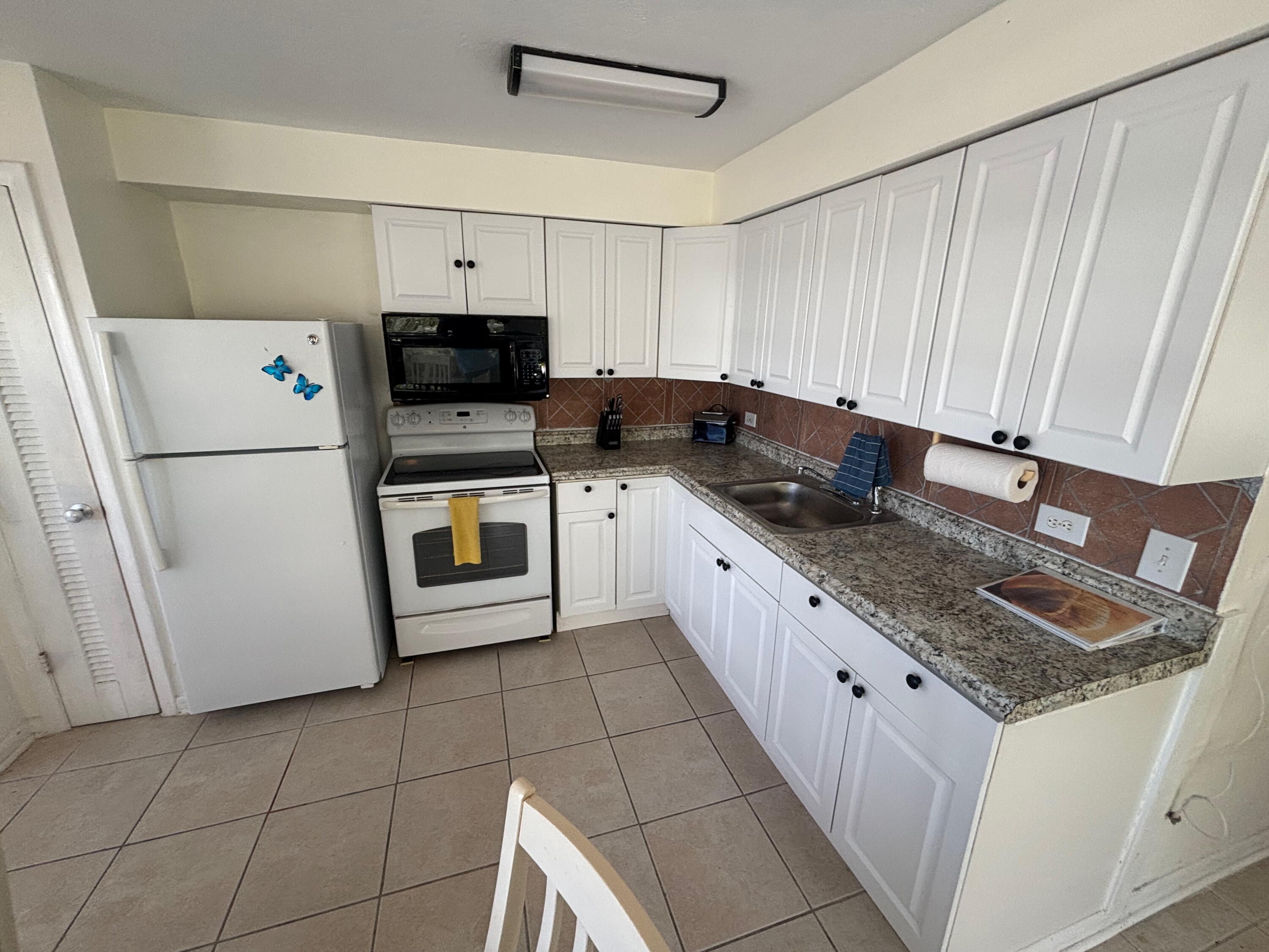 1433 Sunset Road Big Pine Key, FL 33043 - Photo 11 of 18 a kitchen with granite countertop a sink a stove top oven a refrigerator and cabinets