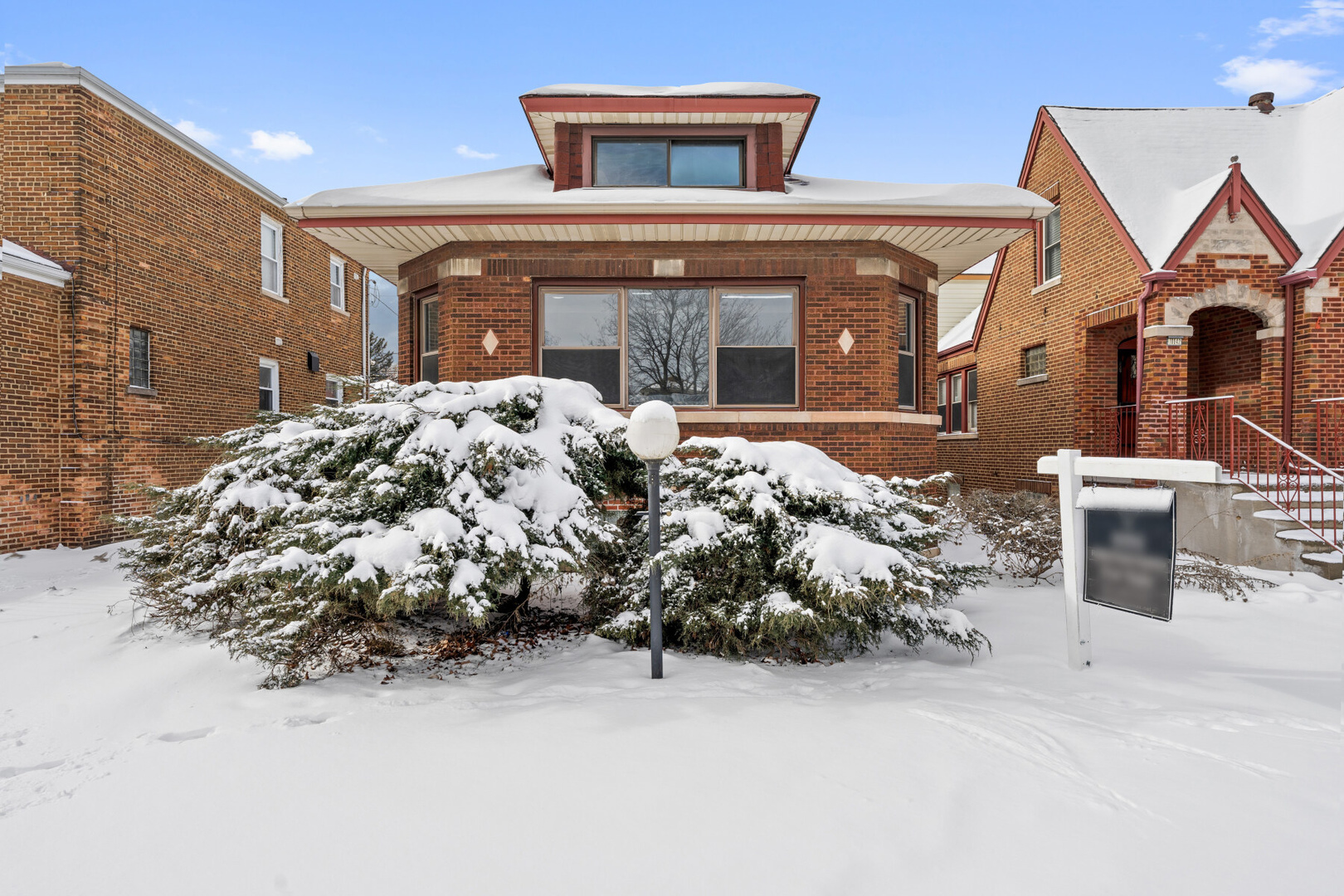a front view of a house with a yard covered with snow