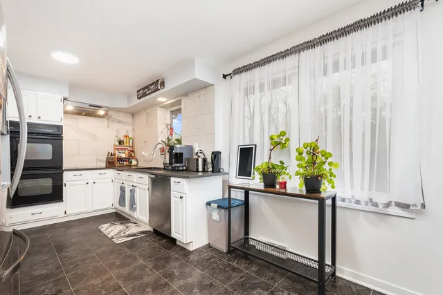 a kitchen with stainless steel appliances a white cabinets and wooden floor