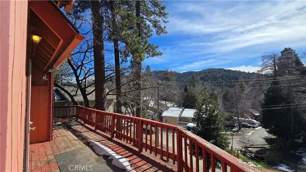 a balcony with wooden floor and trees in the background