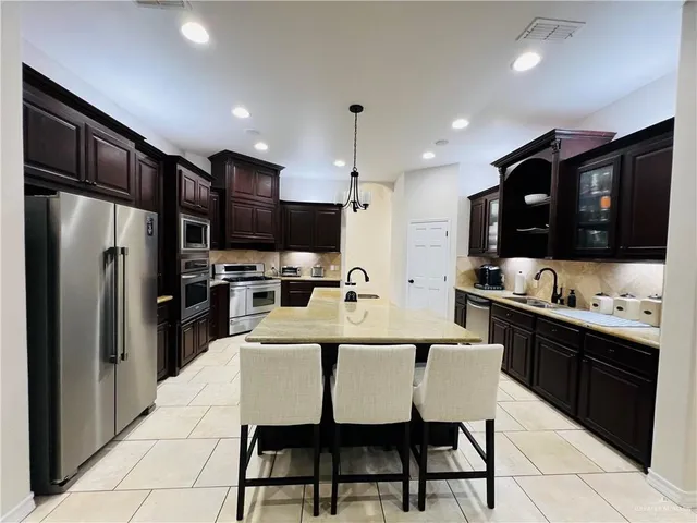 a kitchen with stainless steel appliances a stove a sink a refrigerator and chairs