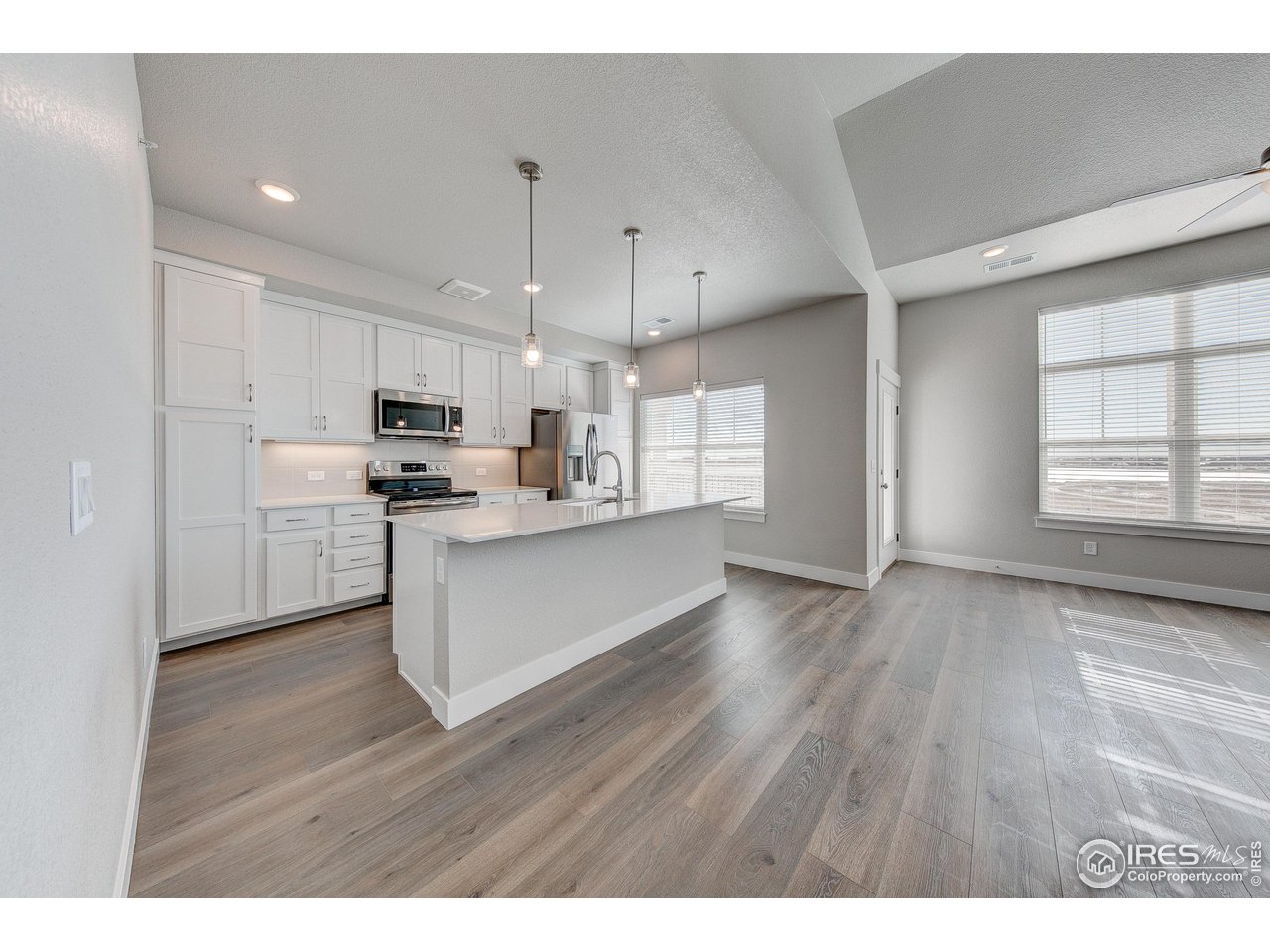 265 High Point Drive, Unit 201 Longmont, CO 80504 - Photo 6 of 26 a kitchen with stainless steel appliances kitchen island wooden floors wooden cabinets and entryway