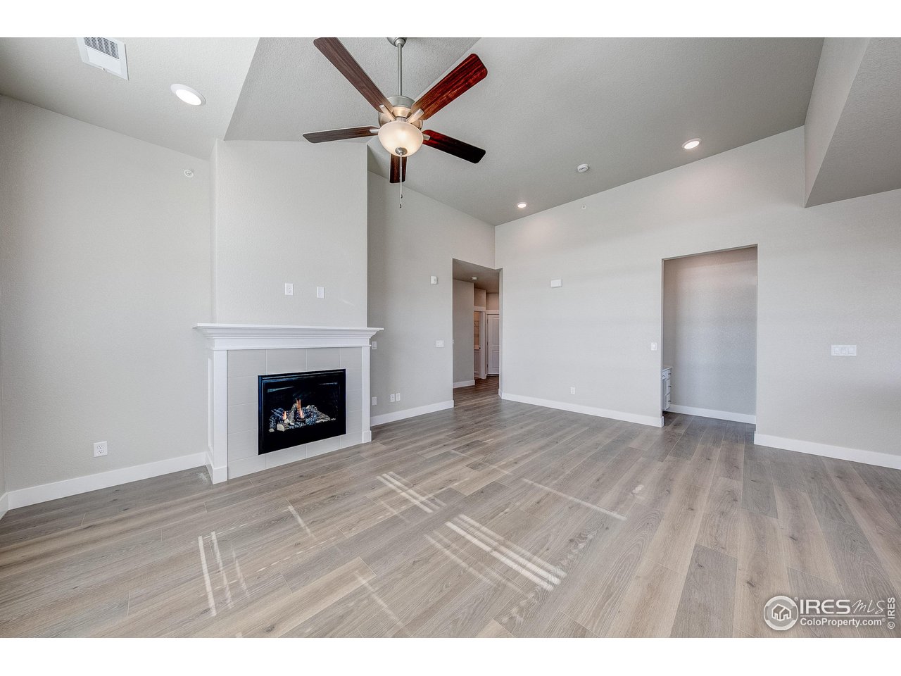 265 High Point Drive, Unit 201 Longmont, CO 80504 - Photo 7 of 26 a view of a livingroom with a fireplace a ceiling fan and wooden floor