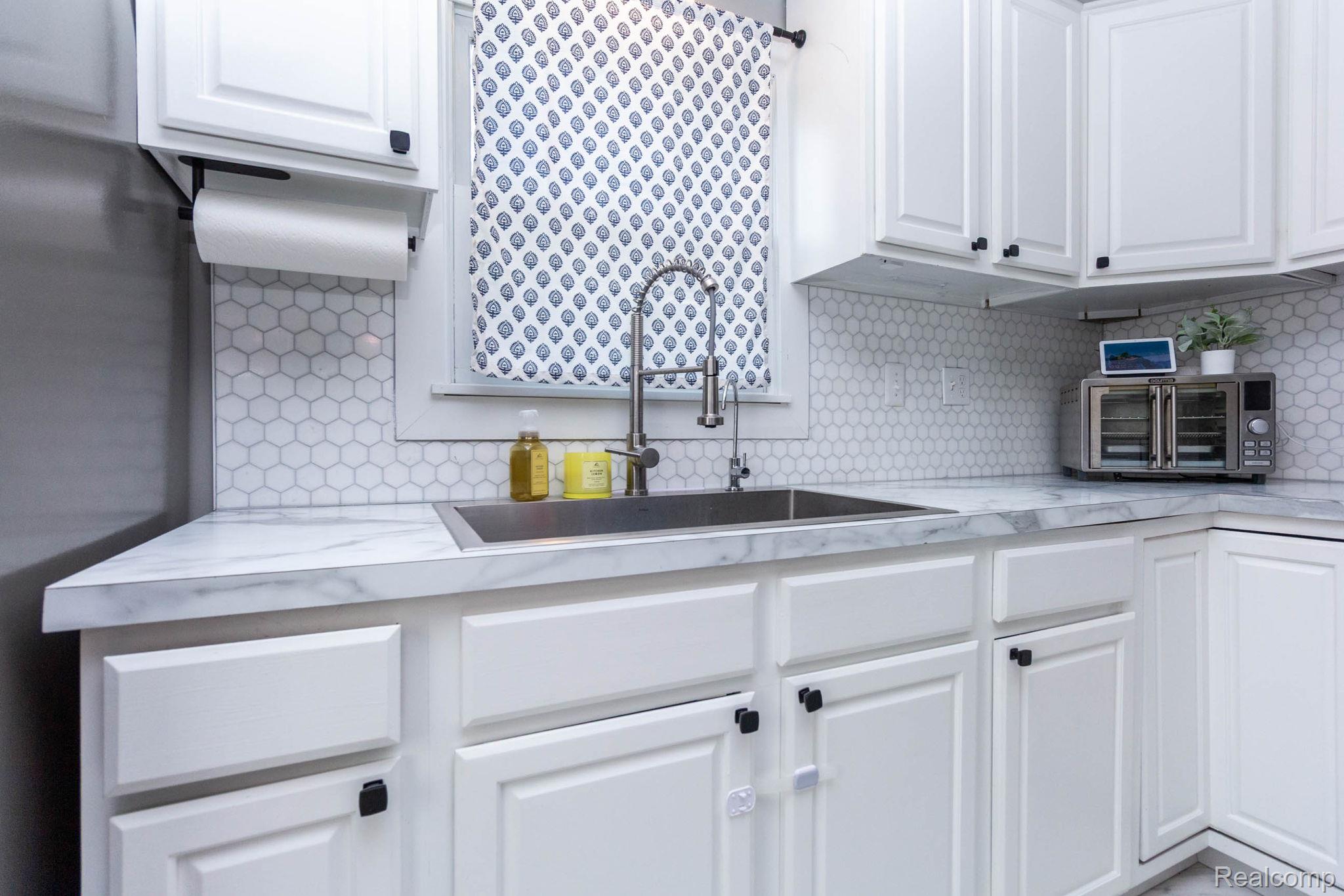 2559 Harrison Avenue Rochester, MI 48307 - Photo 12 of 32 Kitchen featuring white cabinetry with dark hardware, a stainless steel sink, new countertops and tile backsplash