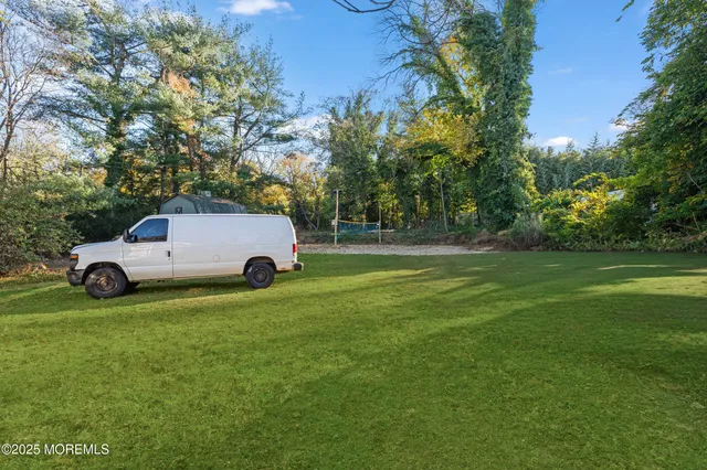 a view of a car parked in the grass with large trees