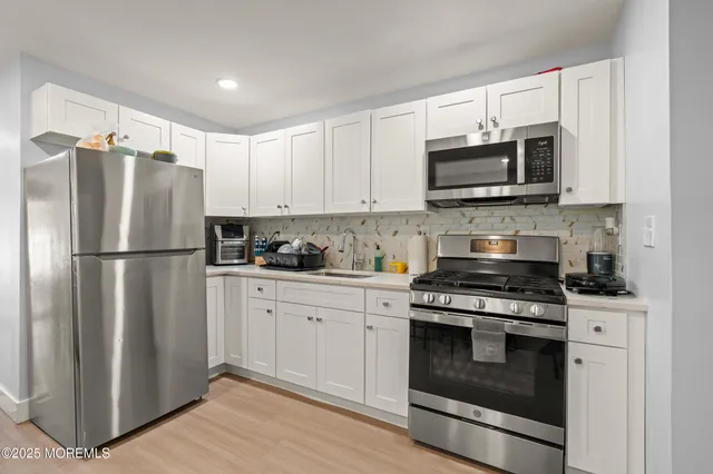 a kitchen with stainless steel appliances granite countertop white cabinets a refrigerator a stove a microwave and cabinets