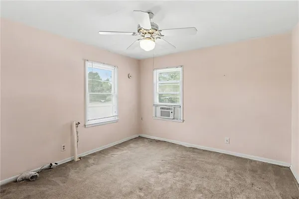 an empty room with a chandelier fan and windows