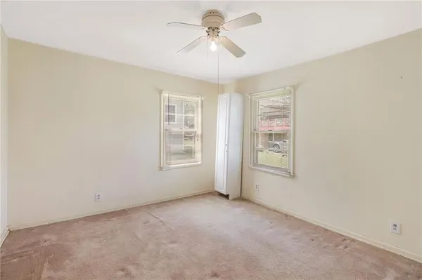 an empty room with windows and fan