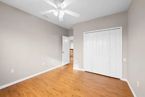 an empty room with wooden floor and ceiling fan