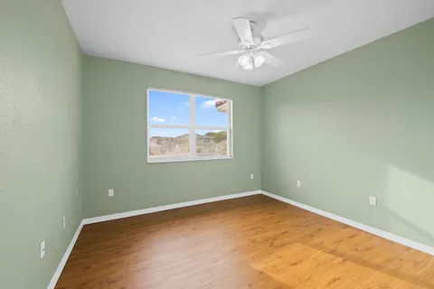 an empty room with wooden floor and a ceiling fan