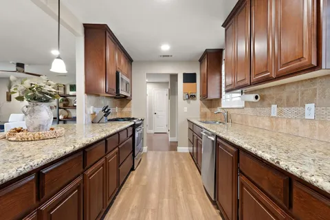 a kitchen with granite countertop stainless steel appliances a sink stove top oven and cabinets