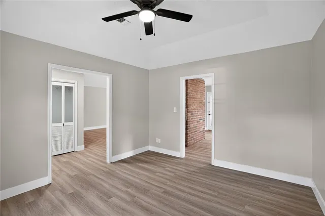 an empty room with wooden floor and ceiling fan