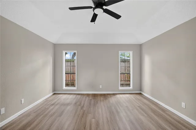 a view of empty room with wooden floor and fan