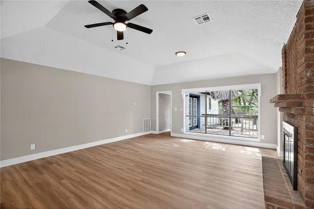 a view of an empty room with a window and wooden floor