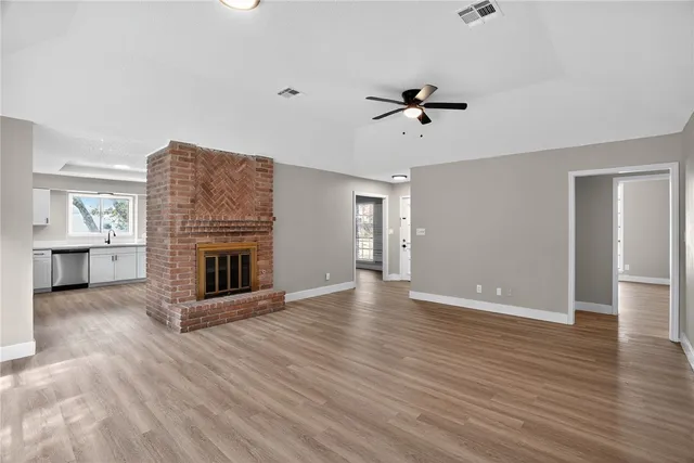 an empty room with wooden floor a fireplace and windows