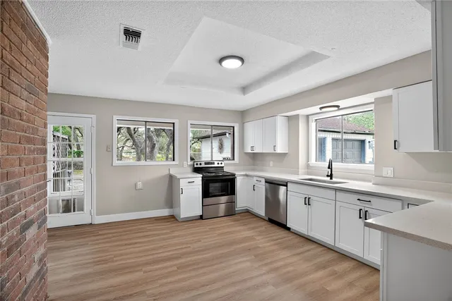 a large kitchen with stainless steel appliances granite countertop a sink cabinets and wooden floor