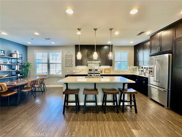 a kitchen with stainless steel appliances granite countertop a dining table chairs stove refrigerator and cabinets