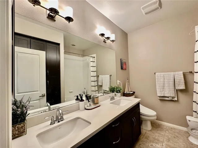 a bathroom with a double vanity sink toilet and mirror