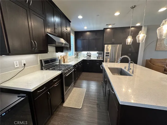 a kitchen with stainless steel appliances kitchen island granite countertop a sink a stove and a refrigerator