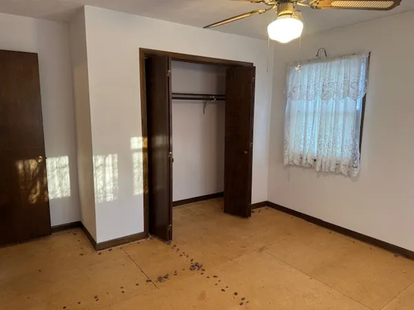 an empty room with windows and fan