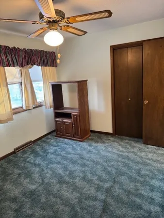 an empty room with a fan and a large window