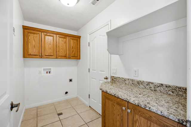 1630 East 2450th Street South, Unit 263 St. George, UT 84790 - Photo 18 of 24 Laundry area featuring a built-in granite-finish countertop, wood-finish cabinetry, tile flooring, and integrated wall shelving