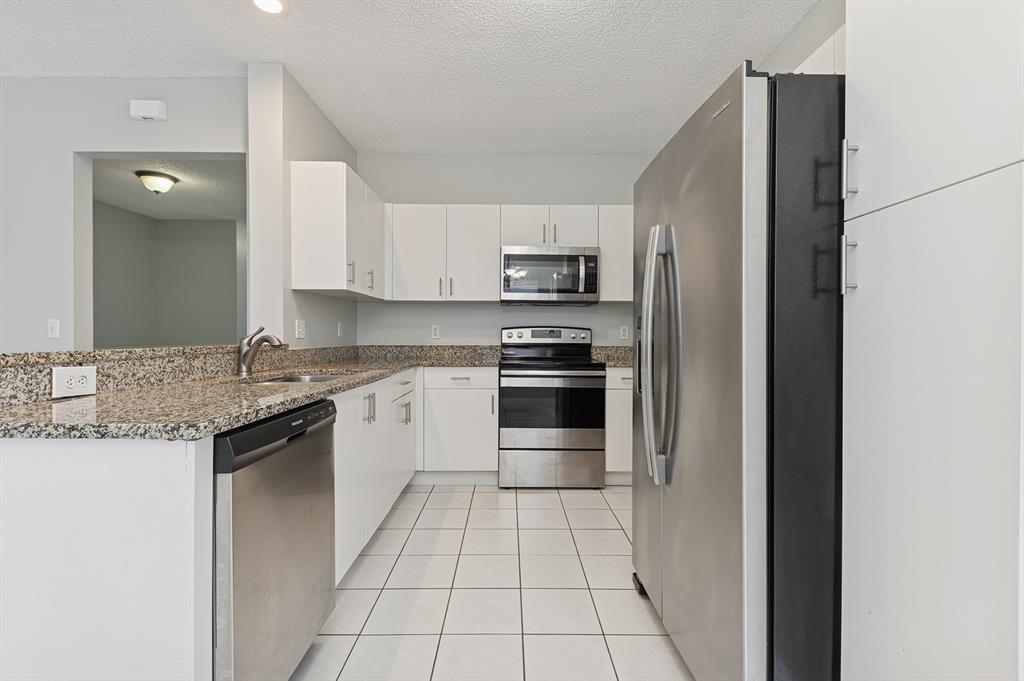 6007 Red Plum Court, Unit 465 Tamarac, FL 33321 - Photo 11 of 23 a kitchen with stainless steel appliances granite countertop a refrigerator and a stove