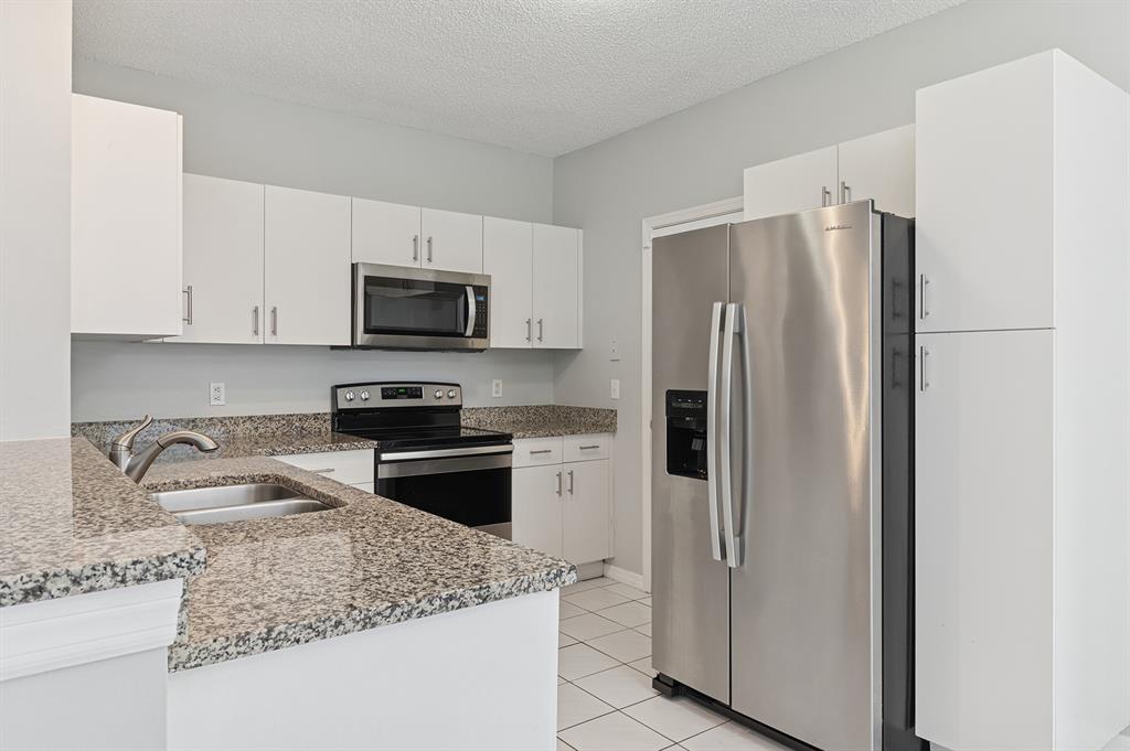 6007 Red Plum Court, Unit 465 Tamarac, FL 33321 - Photo 10 of 23 a kitchen with granite countertop a refrigerator stove and microwave