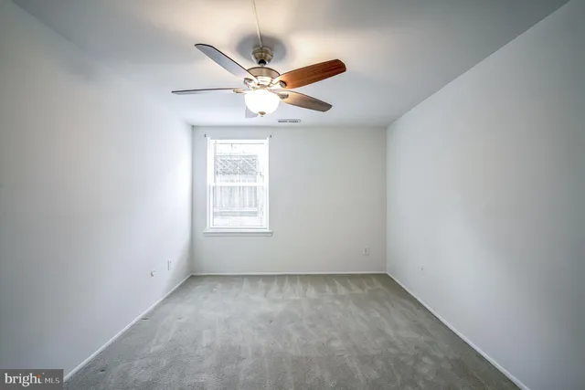 an empty room with a window and ceiling fan