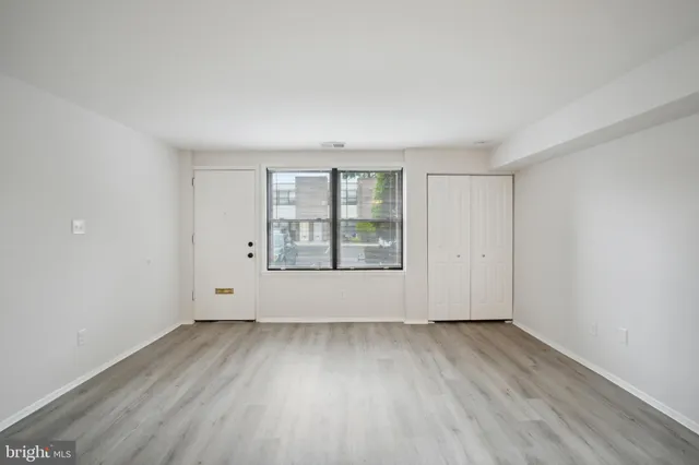 an empty room with wooden floor and windows