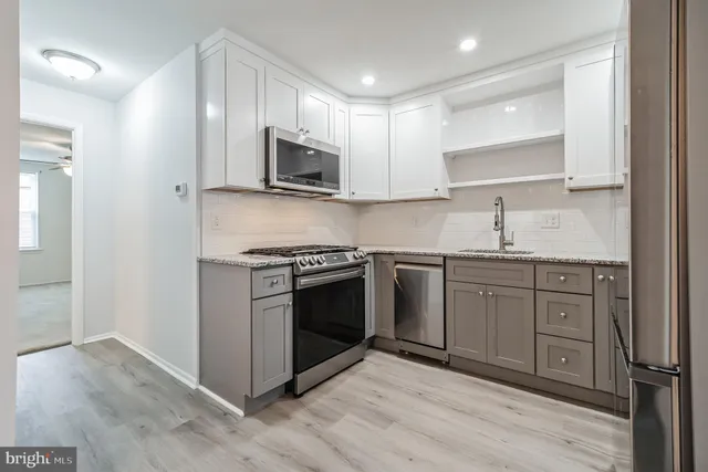 a kitchen with stainless steel appliances granite countertop a stove a sink and a microwave