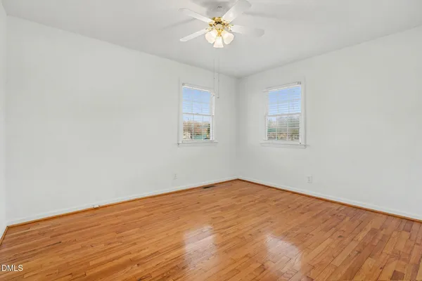 an empty room with wooden floor and ceiling fan