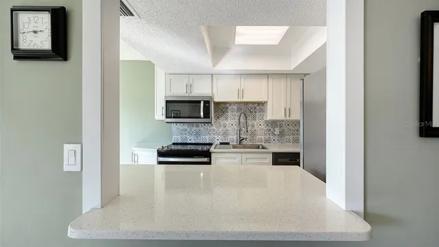 a kitchen with stainless steel appliances a stove a microwave a sink and cabinets