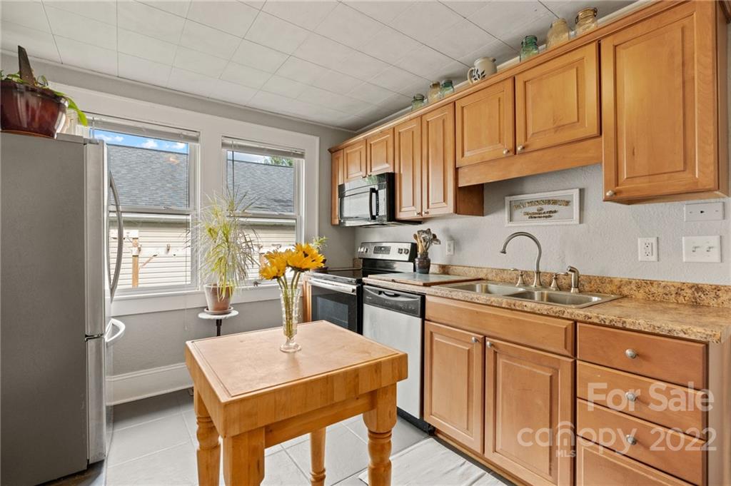 136 Round Top Road Asheville, NC 28803 - Photo 16 of 34 a kitchen with stainless steel appliances granite countertop a stove a sink dishwasher and a refrigerator with wooden cabinets