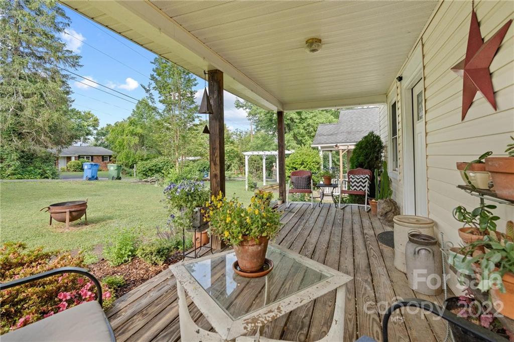 136 Round Top Road Asheville, NC 28803 - Photo 7 of 34 a view of a patio with table and chairs potted plants with wooden floor and fence