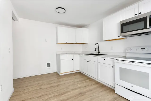 a kitchen with granite countertop white cabinets and white appliances