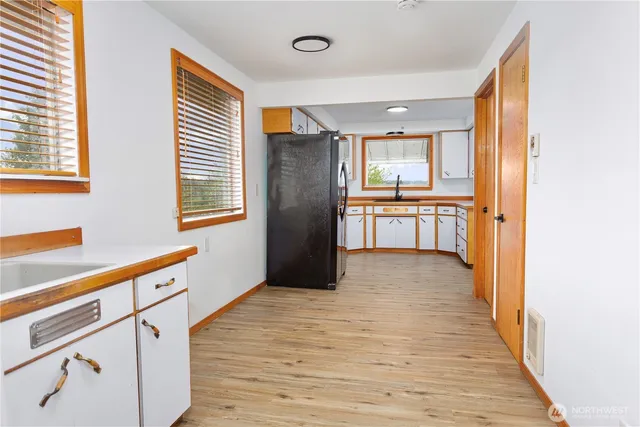 a large kitchen with granite countertop a refrigerator a sink and dishwasher with wooden floor