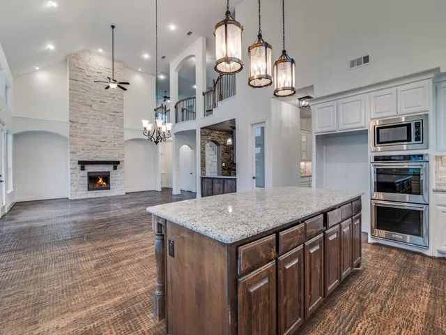 a kitchen with stainless steel appliances granite countertop a kitchen island a stove and a wooden cabinets