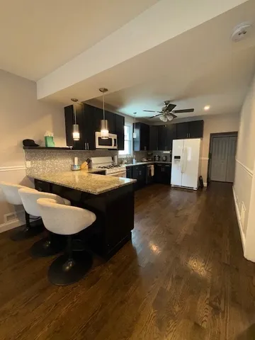 a living room with stainless steel appliances furniture a rug and a view of kitchen