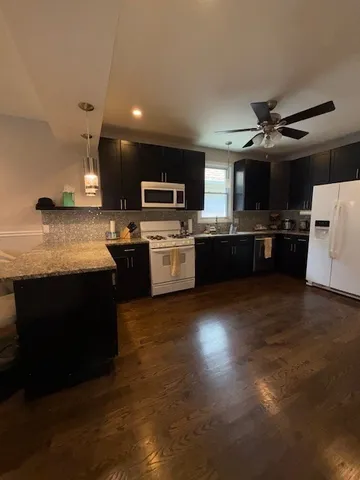 a kitchen with kitchen island granite countertop a stove top oven a sink dishwasher a dining table and chairs with wooden floor