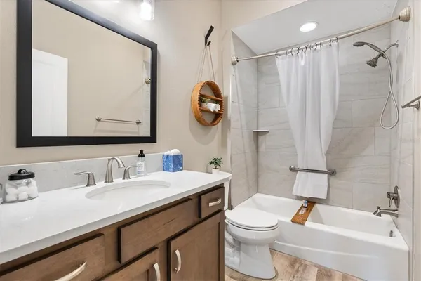 a bathroom with a sink a toilet a mirror a vanity and shower