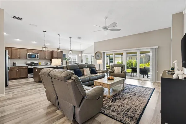a living room with furniture kitchen view and a wooden floor
