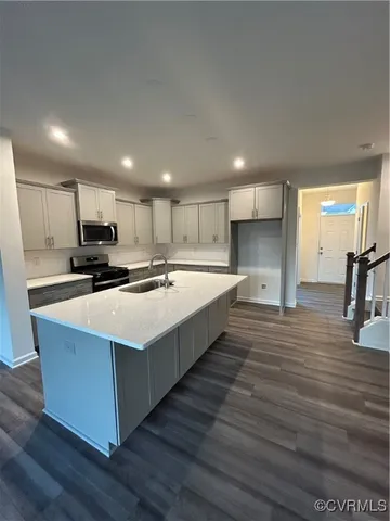 a large kitchen with kitchen island a sink dishwasher a refrigerator and a stove with wooden floor