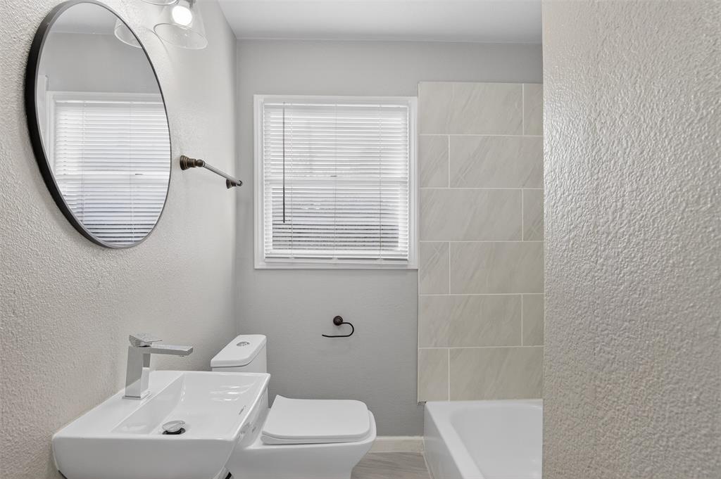 4721 Tremont Street Dallas, TX 75246 - Photo 12 of 22 a bathroom with a toilet a sink a mirror and a window