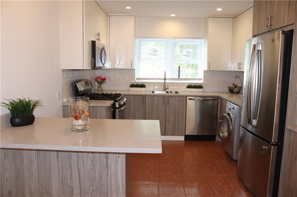 a kitchen with stainless steel appliances a sink a stove a refrigerator cabinets and a counter top space