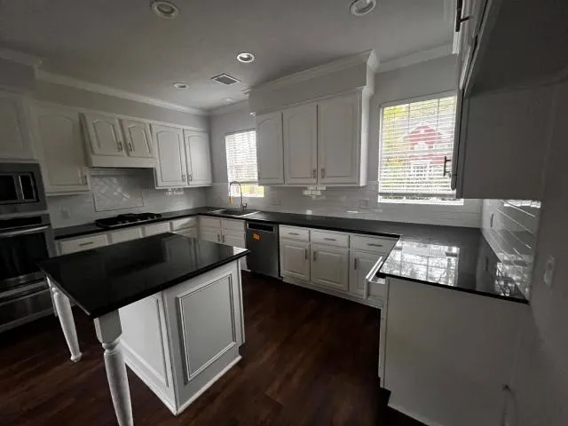 a kitchen with granite countertop a sink stove and cabinets